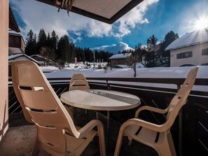 A covered outdoor seating area with a table and chairs, overlooking a snowy landscape with trees and buildings. - Haus Sunneschy Whg. 202 Appartement/Fewo, Dusche, WC 2.5  Zimmerwohnung/ Whg.202 by Interhome (Parpan)