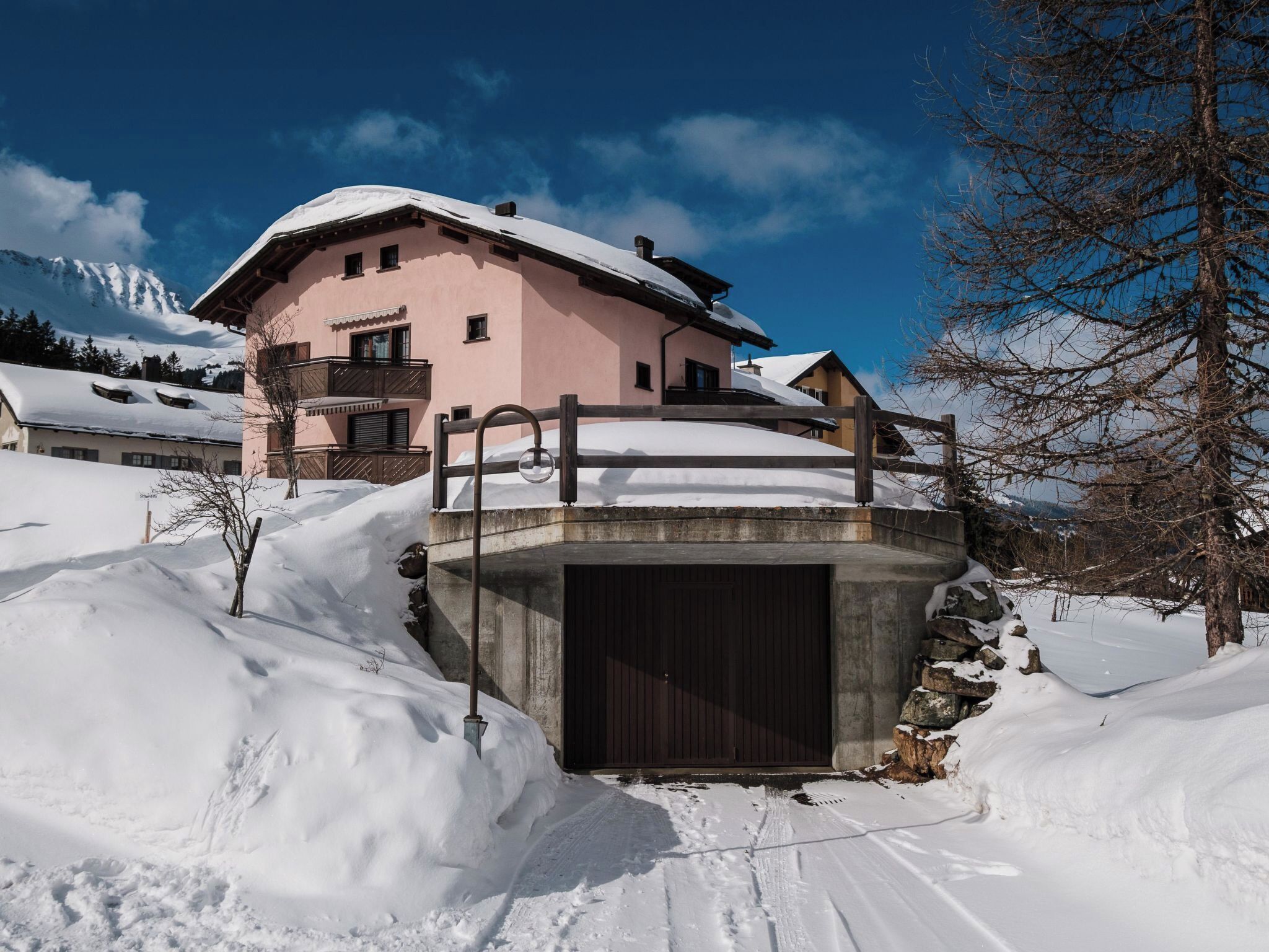 A snow-covered building with a balcony and a concrete structure in front.