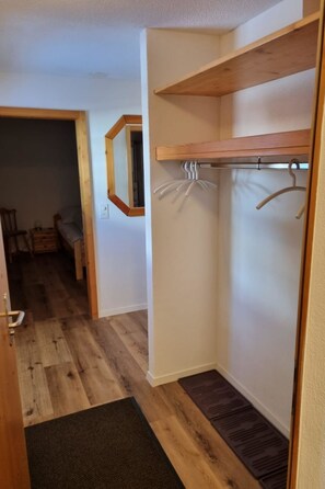 Ein Flur mit Holzboden, einem Kleiderständer und einer Tür zu einem anderen Raum.