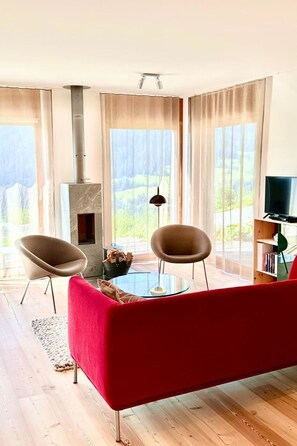 A modern living room with a red sofa, two armchairs, a glass coffee table, a fireplace, and a television. - Pas-Cheus Appartement/Fewo, Bad, WC, 2 Schlafräume by Interhome (Vaz)