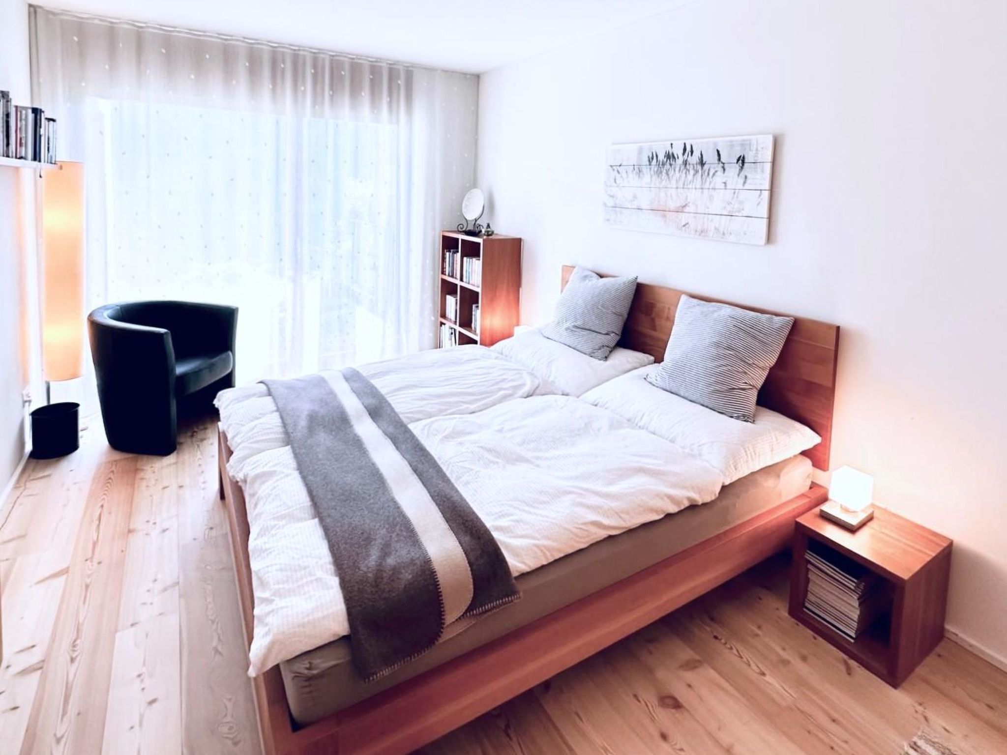 Un dormitorio moderno con una cama de madera, una mesita de noche, una silla y una estantería.