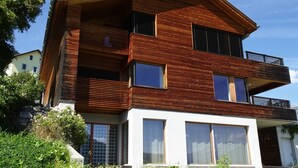 Uma casa moderna de vários andares com fachada de madeira, janelas amplas e varandas.