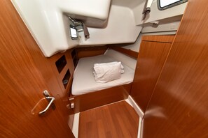 A compact cabin with a small bed, a wooden door, and a white sink. - Sun-Kissed Sailing Adventure in Zadar, Croatia (Bibinje)