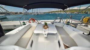 En båts interiör med ett bord i mitten, bekväma sittplatser och utsikt över hamnen.
