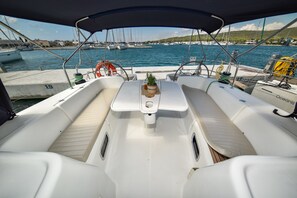 A boat's interior with a central table, cushioned seating, and a view of the marina. - Sun-Kissed Sailing Adventure in Zadar, Croatia (Bibinje)