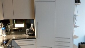 Et kompakt køkken med hvide skabe, en indbygget komfur og en mikroovn.
