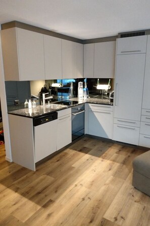 A modern kitchen with white cabinetry, a black countertop, and a dishwasher. - Haus Sunneschy Whg. 301 Appartement/Fewo, Dusche, WC, 3 Schlafräume by Interhome (Parpan)