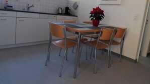 Una cocina con una mesa y sillas, una planta en maceta y un ventanal.