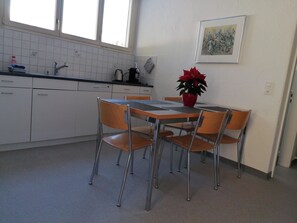 Eine Küche mit Esstisch, Stühlen, einem Blumentopf und einem Fenster.