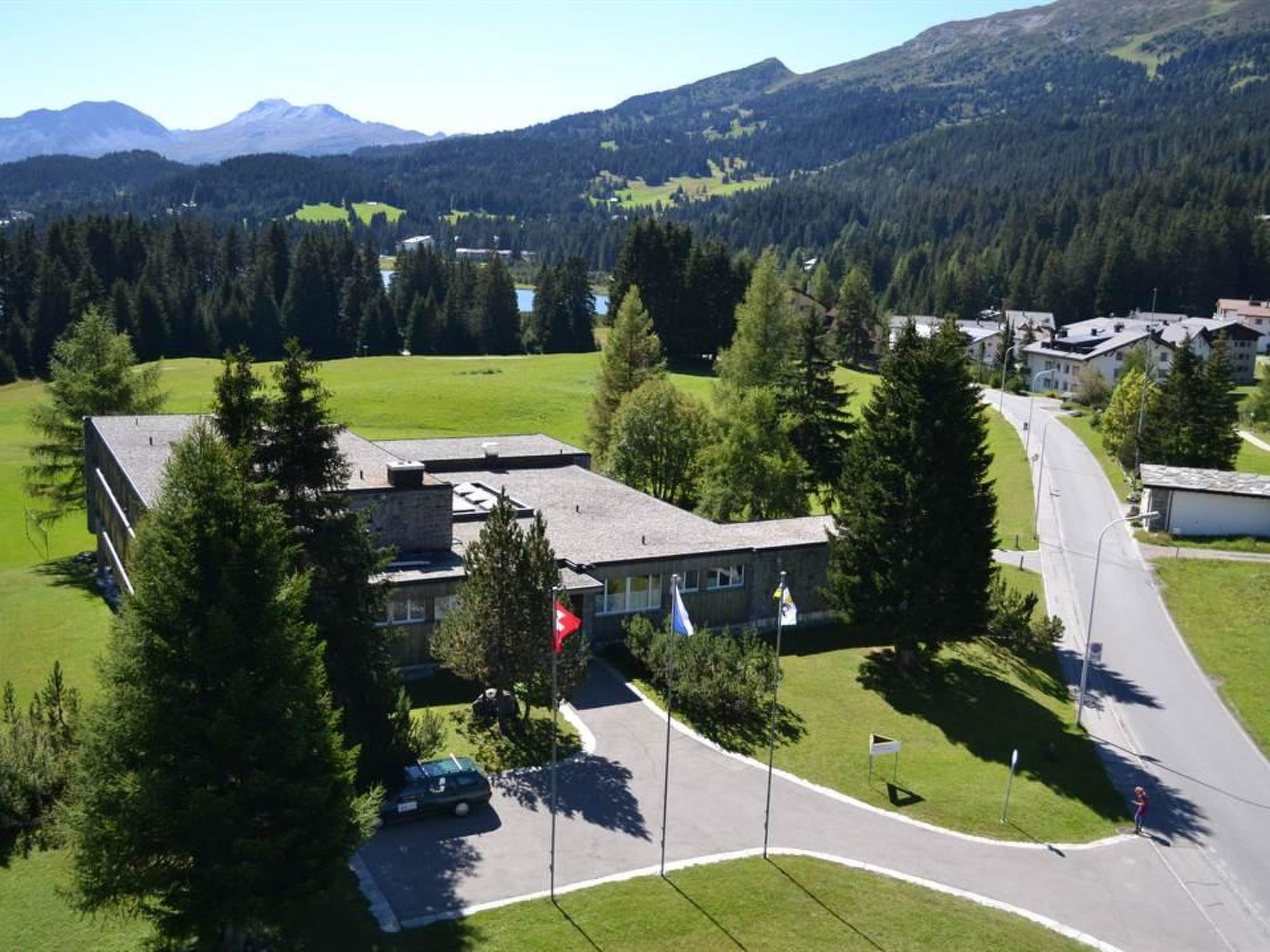 A building with a flat roof, surrounded by trees and a road.