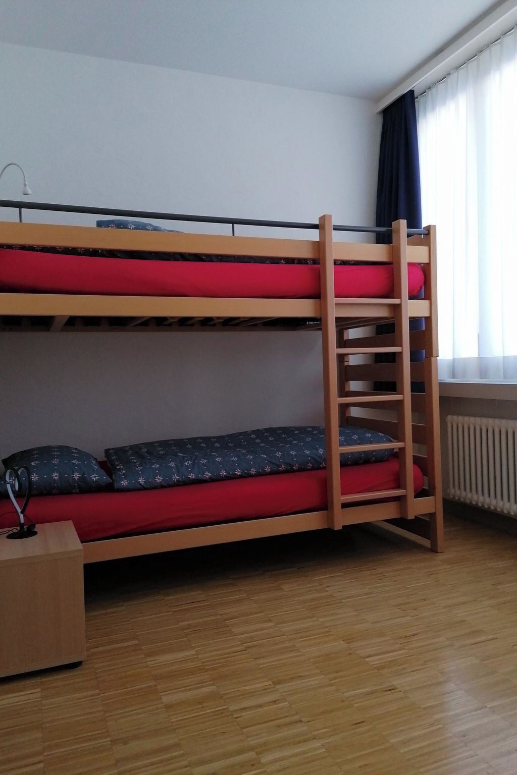 Ein Stockbett mit einer Leiter, einem Schreibtisch und einer Heizung.