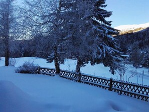 Eine verschneite Landschaft mit Holzzaun und Bäumen.