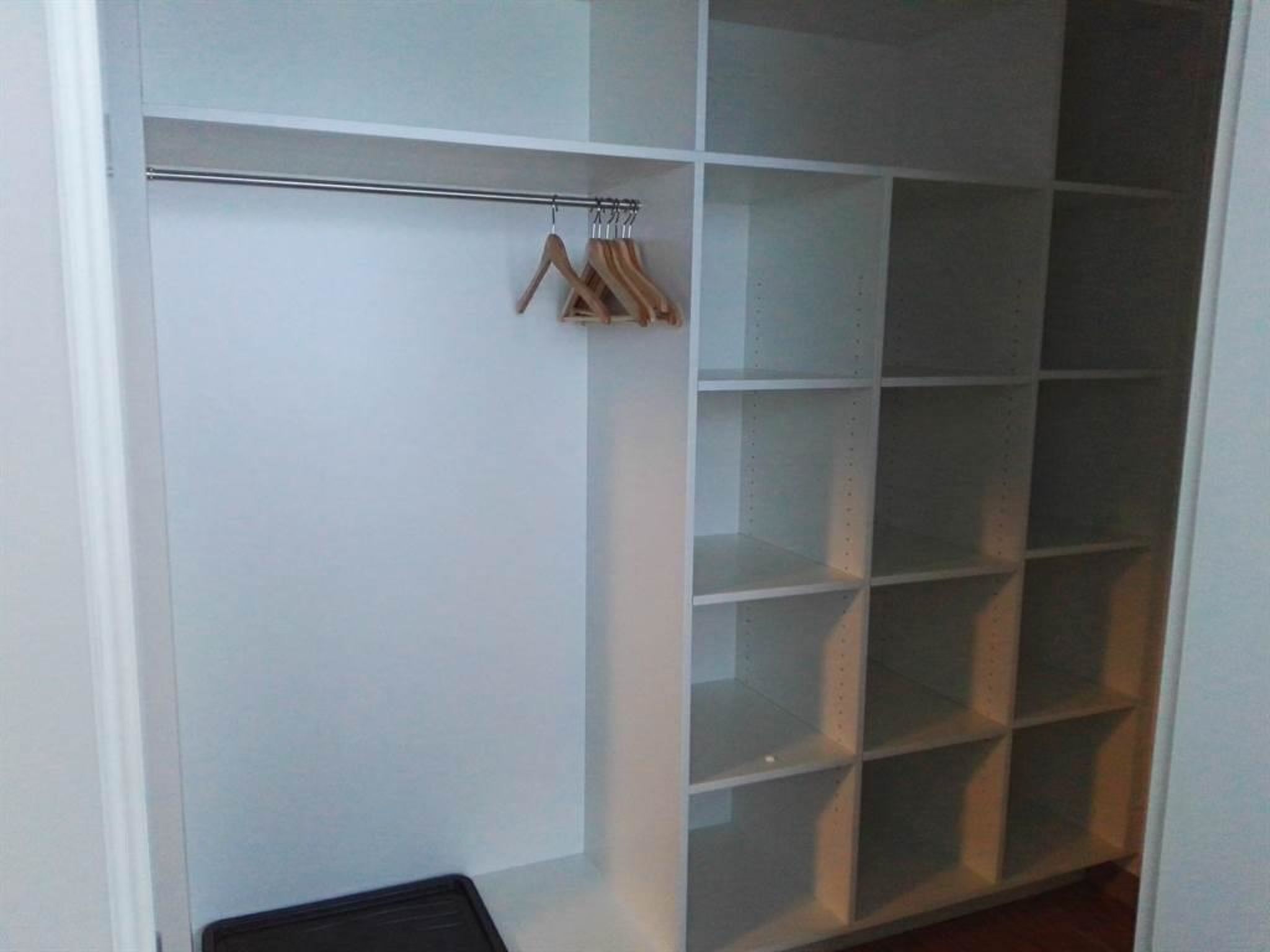 En rummelig garderobe med åbne hylder og en bøjlestang.