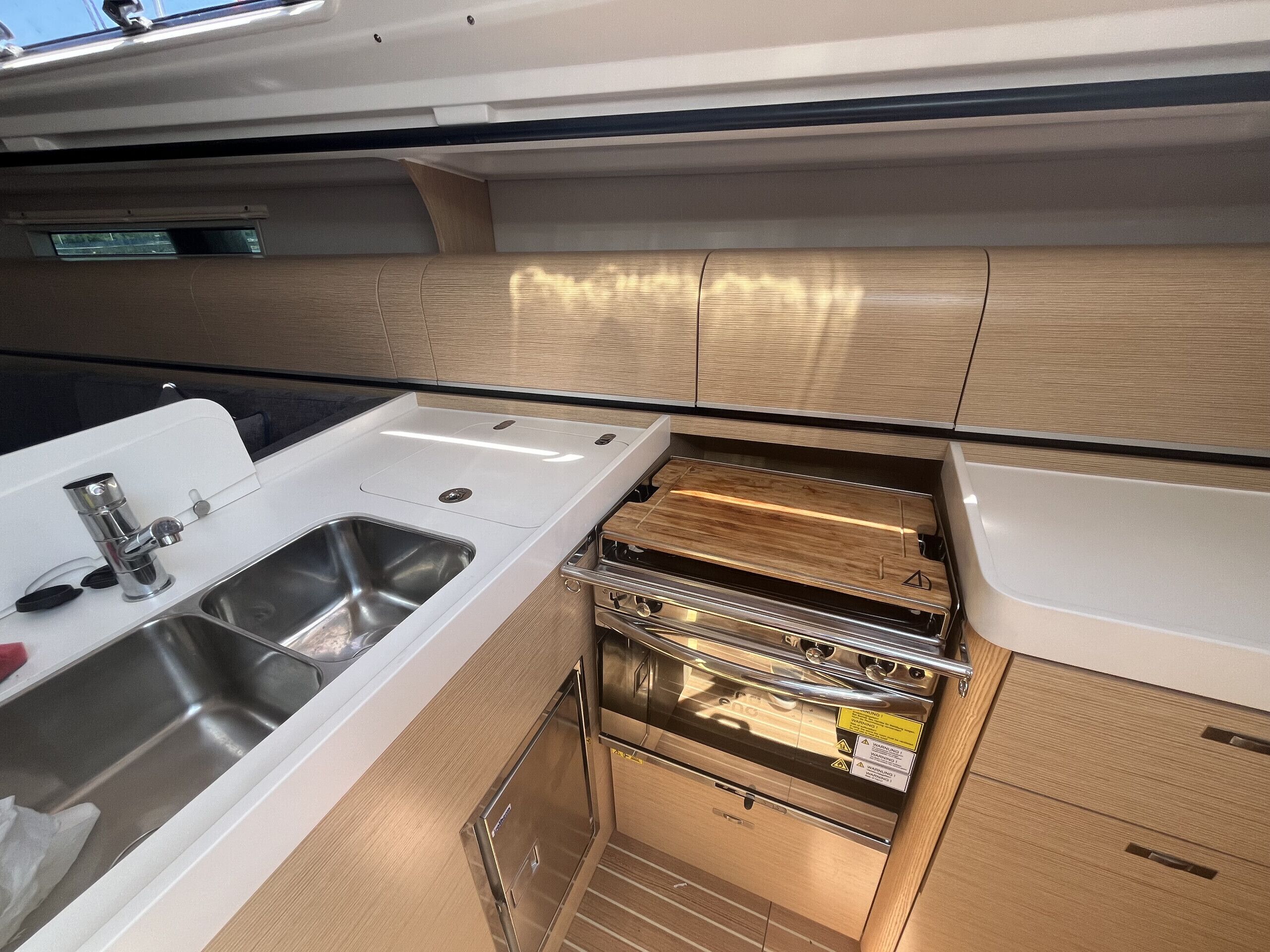 Une cuisine compacte dotée d’un évier, d’appareils électroménagers en acier inoxydable et de meubles en bois.