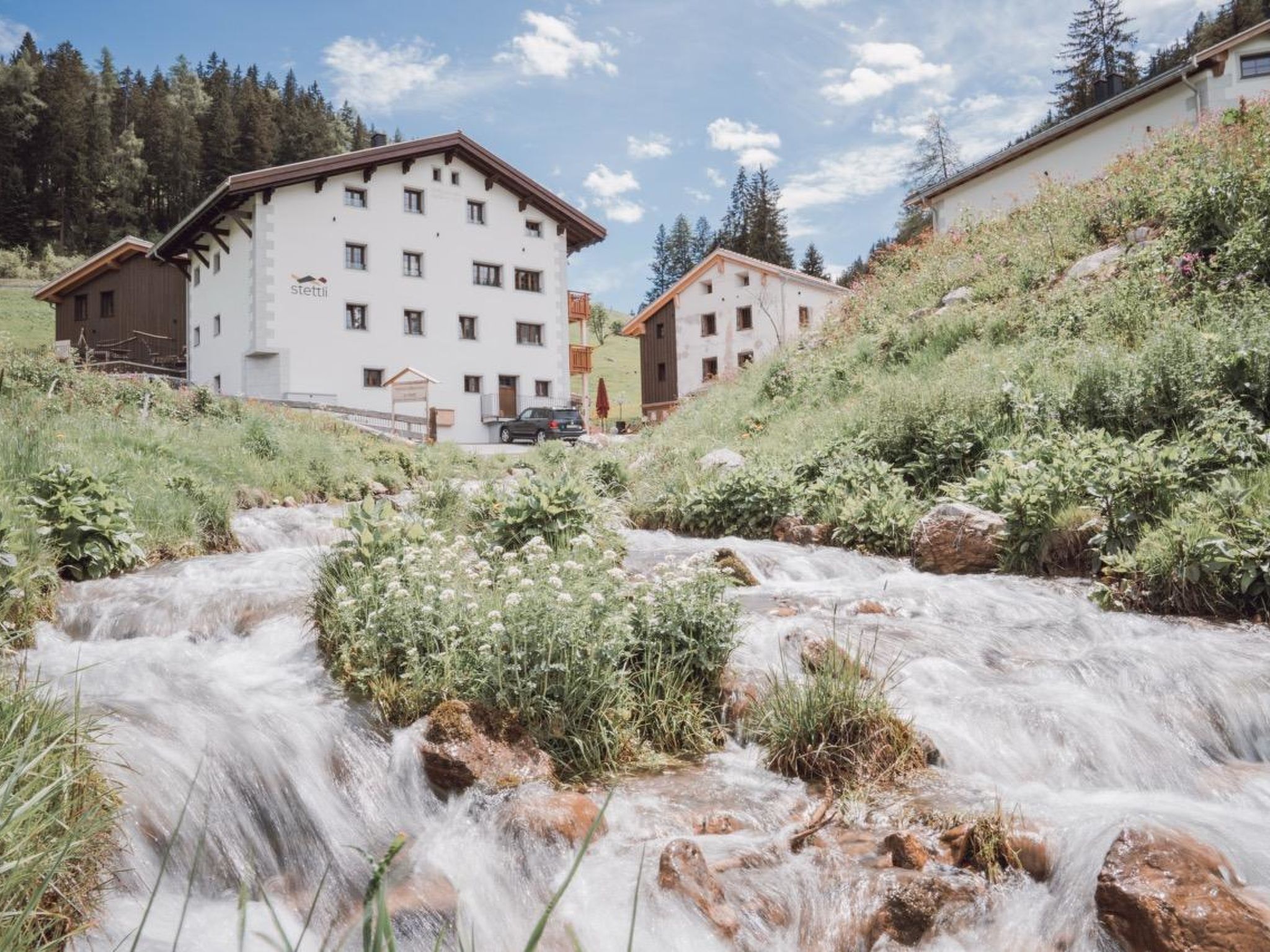 Un hôtel à la façade blanche, doté de nombreuses fenêtres et situé dans un bâtiment adjacent à un ruisseau.
