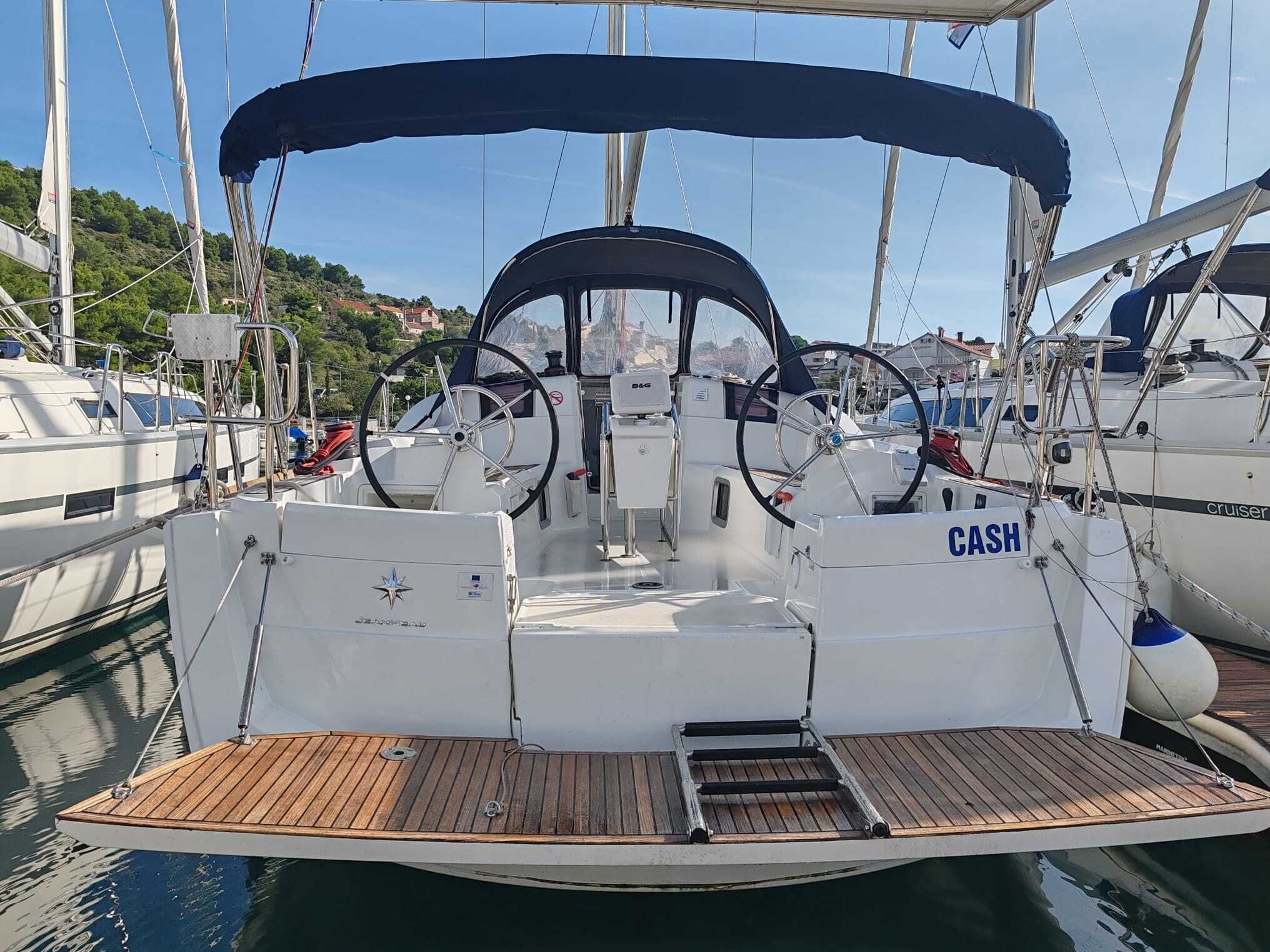 Un pont de bateau équipé d’un volant, d’une plaque portant l’inscription « CASH », et d’une petite plateforme en bois.