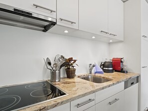 Una cucina moderna con piano cottura integrato, lavello in acciaio inossidabile e mobili bianchi.