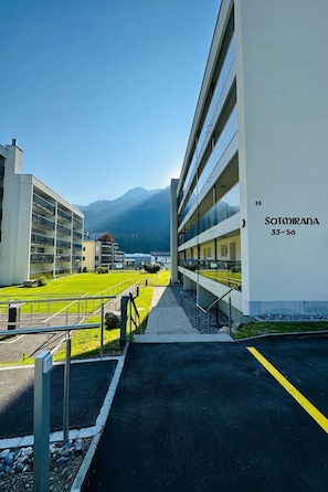 Un moderno edificio hotel con diversi piani, cielo sereno e una montagna sullo sfondo.