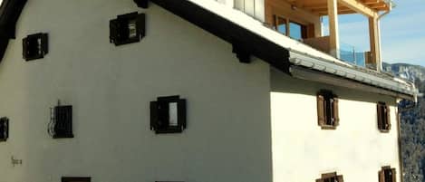 Ein zweistöckiges Gebäude mit Balkon, Holztür und mehreren Fenstern.
