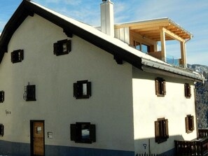 A two-story building with a balcony, a wooden door, and multiple windows. - Ferienhaus Tgioc Ferienhaus, Dusche und Bad, WC, 4 oder mehr Schlafräume by Interhome (Vaz)