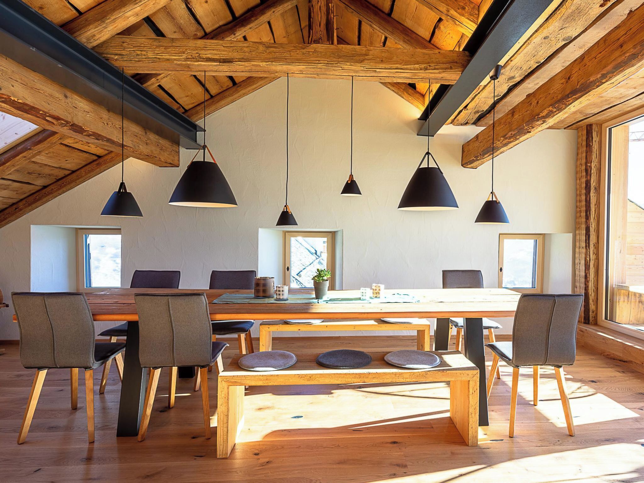 A dining area with a wooden table, chairs, and pendant lights.