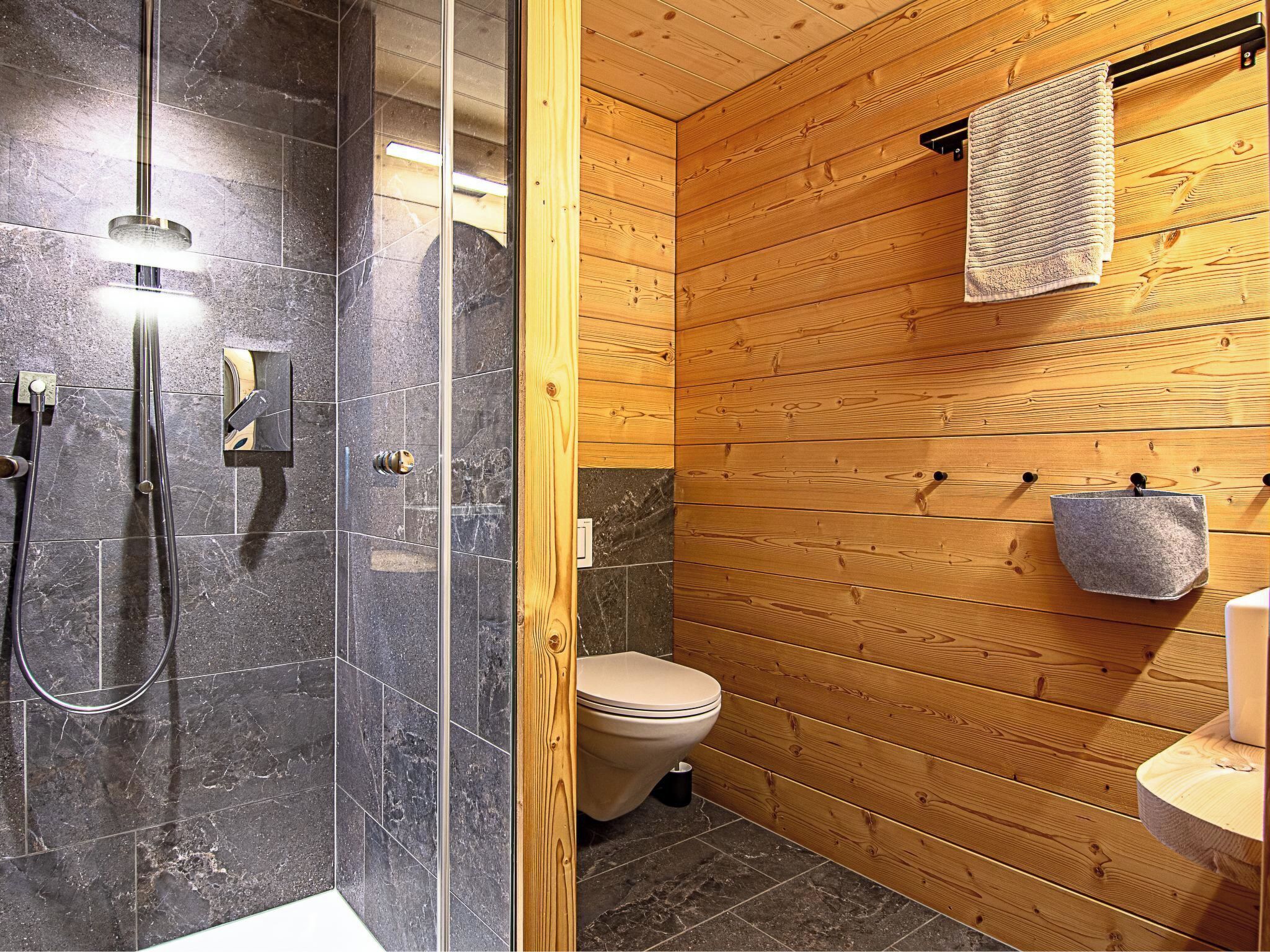 A bathroom with a shower, toilet, and wooden paneling.