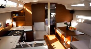A compact kitchen with a stove, sink, and a small dining area with a table and chairs. - Sibenik Sun-soaked Sailing: A Luxurious Croatian Voyage (Pirovac)
