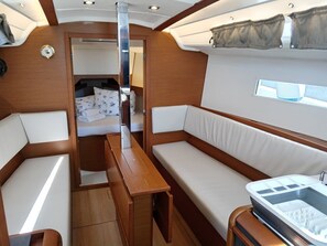 A compact interior with a bed, a sofa, a small table, and a built-in sink. - Sibenik Sun-soaked Sailing: A Luxurious Croatian Voyage (Pirovac)