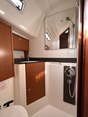 A compact bathroom with a sink, mirror, and shower.