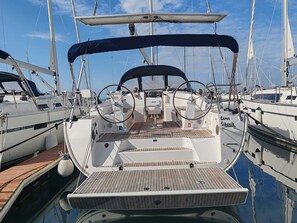Ein Yachthafen mit mehreren Segelbooten, die an einem hölzernen Steg festgemacht sind, mit Steuerpult und Sonnensegel.