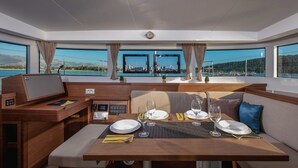 A yacht interior with a dining area, control panel, and large windows offering a view of the sea and landscape. - Sun-Kissed Sailing Adventure in Split, Croatia (Kaštel Gomilica)