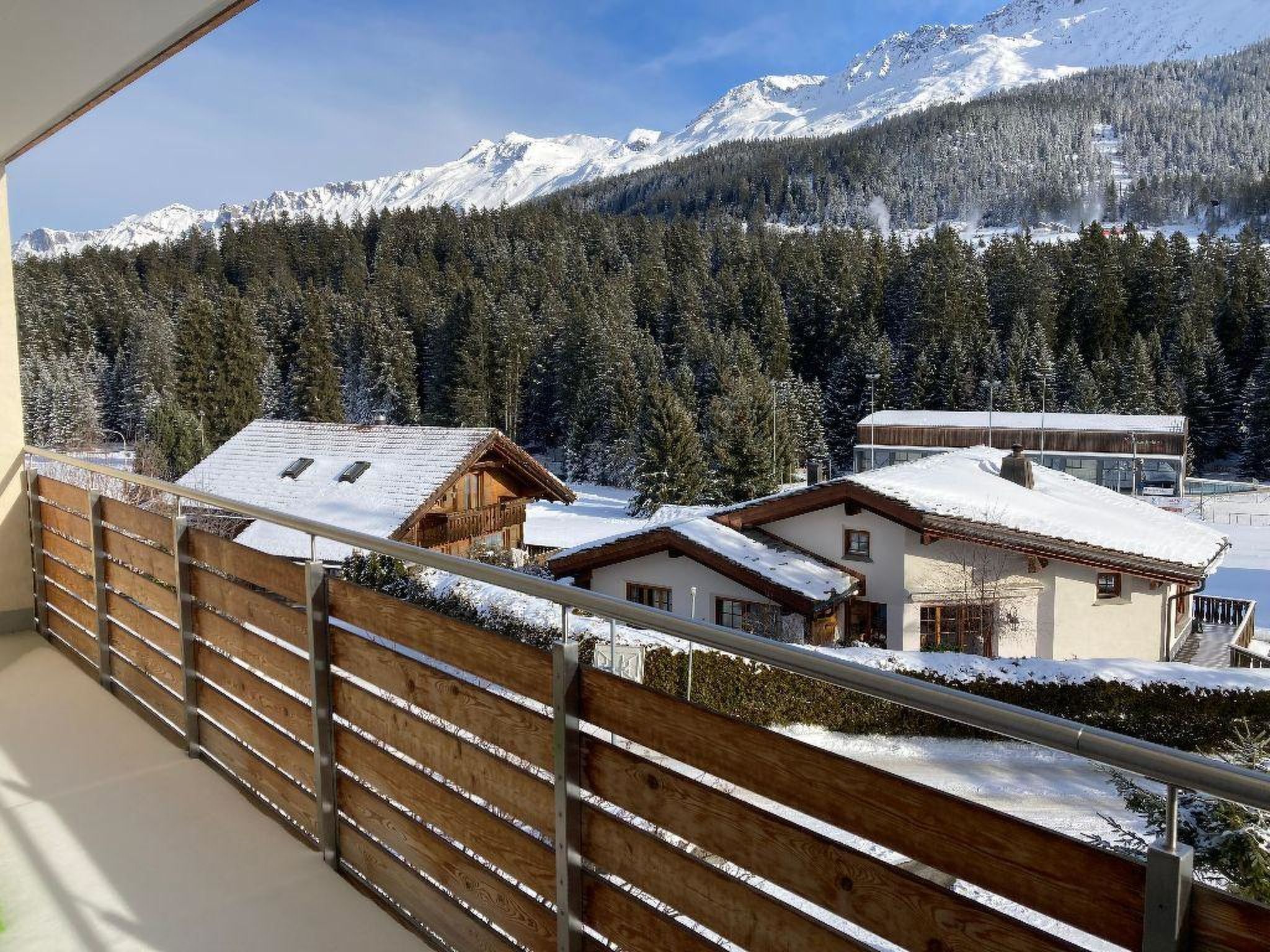 A mountain view with snow-covered houses and a wooden fence.