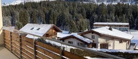 A mountain view with snow-covered houses and a wooden fence.