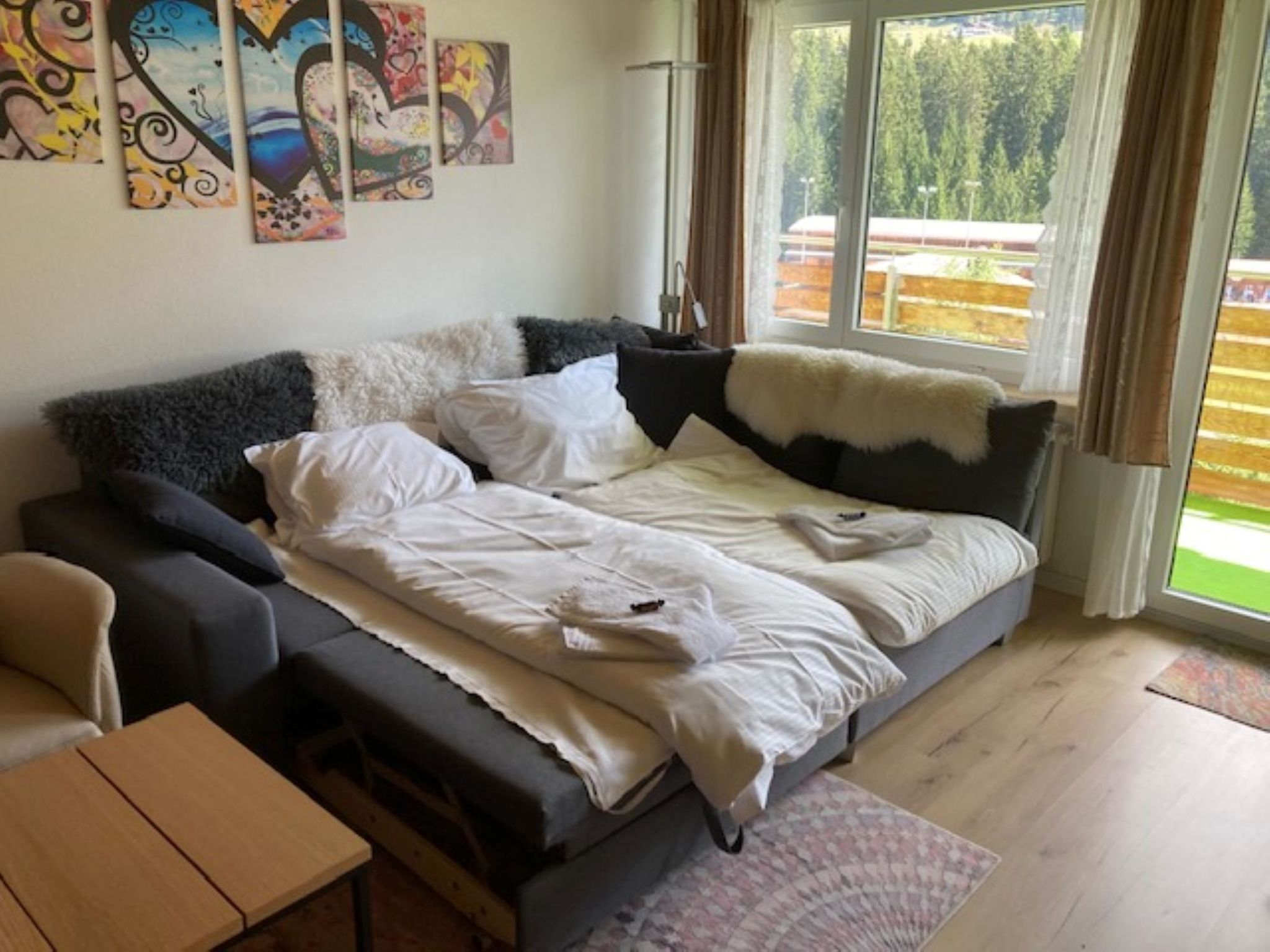 A modern bedroom with a sofa bed, a small table, and artwork on the wall.