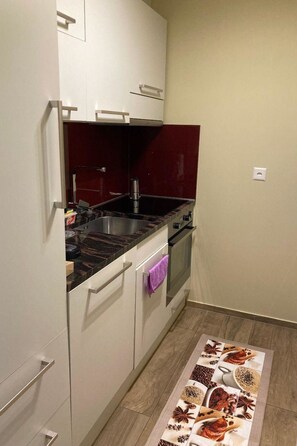 Una cocina compacta con estufa, lavamanos y armarios.
