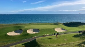 Um campo de golfe com bunkers e vista para o oceano.