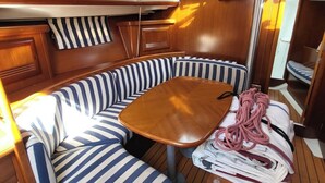 En stuga med ett träpanelat tak, en randig soffa, ett litet bord och en spegel.
