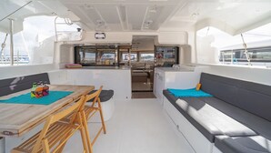 A boat's interior with a dining area, a kitchenette, and a seating area with a view of the marina. - Sun-soaked Sailing Adventure in the Ionian Islands (Perigiali)