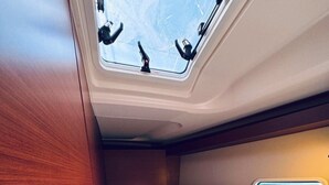 Um pequeno quarto com uma cama de solteiro, um claraboia e uma janela.