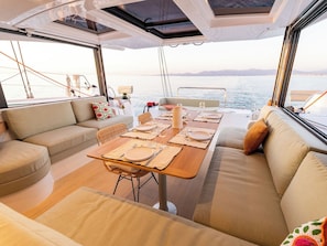 A yacht interior with a dining area, cushioned seating, and a view of the sea. - Sun-Kissed Sailing Adventure in the Ionian Islands, Lefkada (Lefkada)