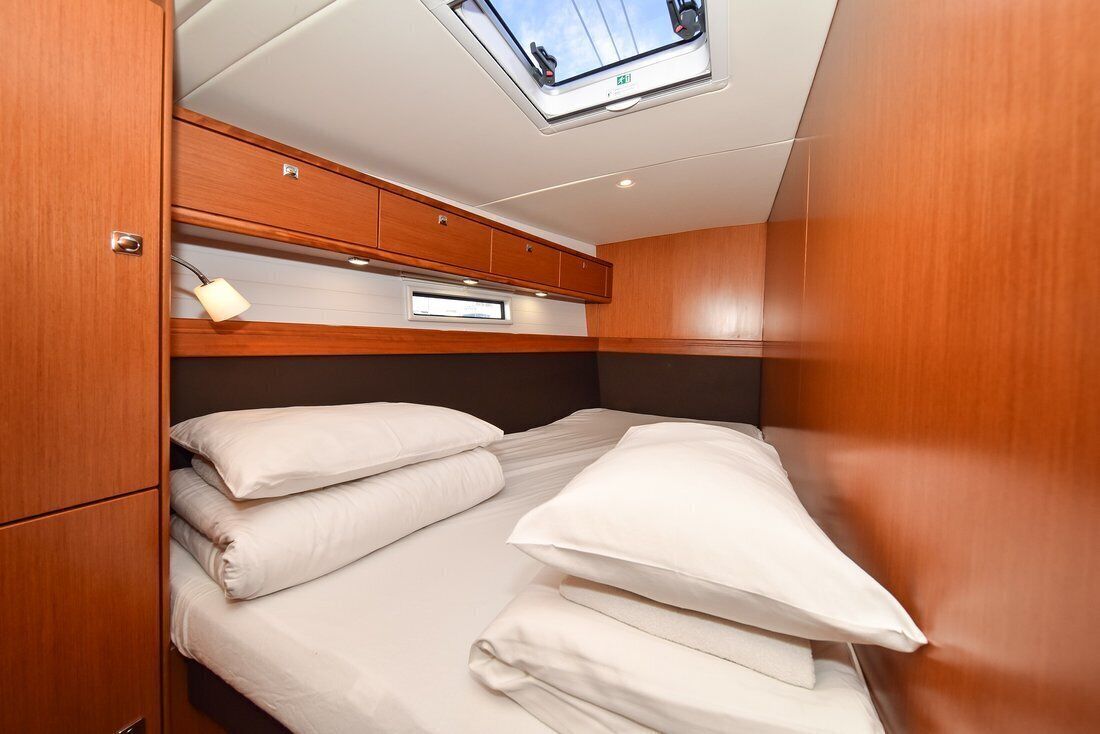 Une petite cabine équipée d’un lit superposé, d’une lucarne et d’un lambris en bois.
