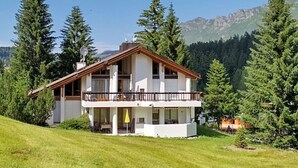 A two-story house with a balcony, surrounded by trees and mountains. - Studio Haus Carmela Lenzerheide Appartement/Fewo, Dusche, WC by Interhome (Lenzerheide)