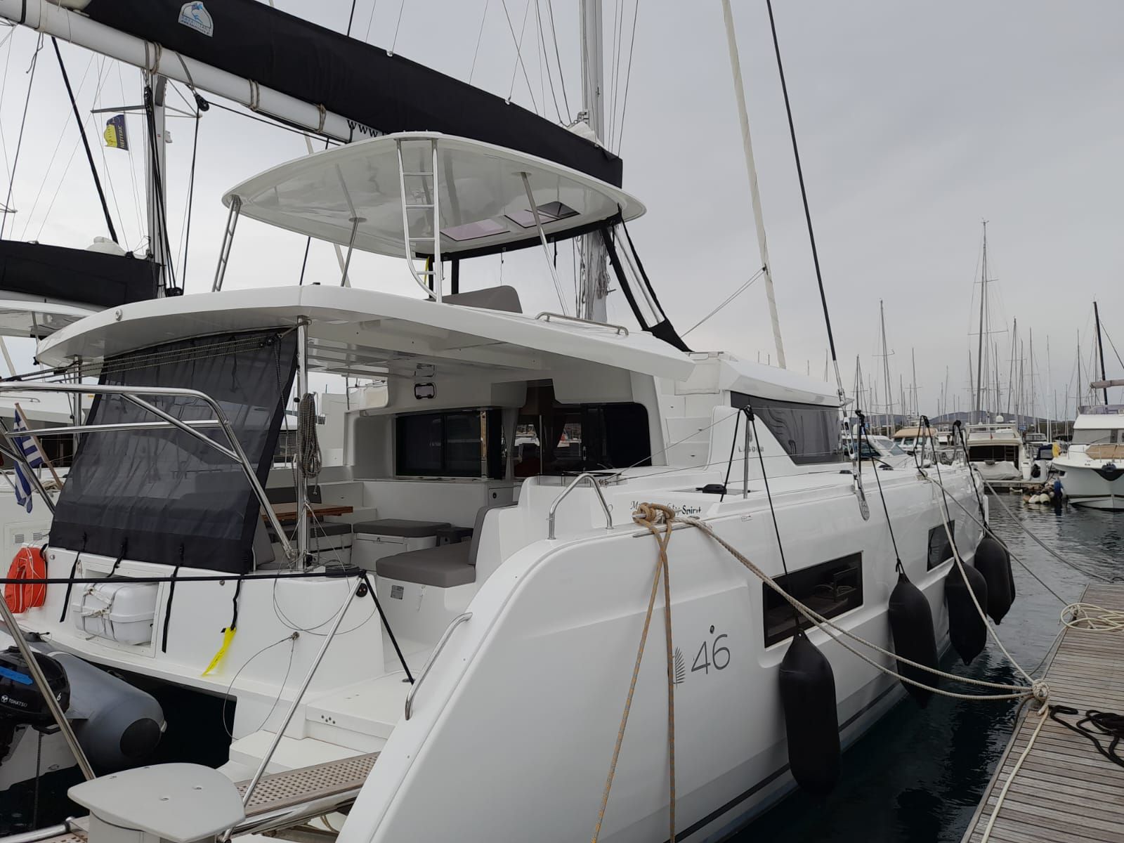 A white yacht docked at a marina with a covered deck area, a seating arrangement, and a number '46' on the side.