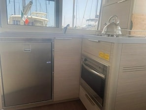 Eine kompakte Küche mit integriertem Kühlschrank, Backofen und Fenster mit Blick auf eine Marina.