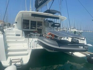Ein Boot mit überdachter Sitzgelegenheit, einem kleinen Schlauchboot und einem Solarpanel.