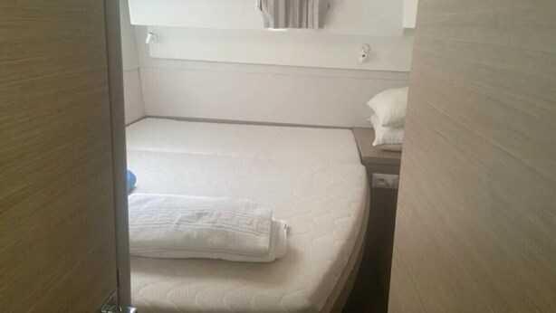 Et lille hotelværelse med en enkelt seng, et lille natbord og en gardinmonteret på væggen.