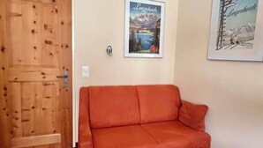 Una habitación con una puerta de madera, un sofá rojo y dos cuadros en la pared.
