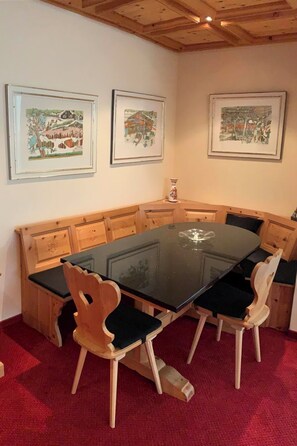 A dining area with a glass-top table surrounded by wooden chairs with cushioned seats. - Haus Colani Ingold Appartement/Fewo,   4-Bettwohnung (3.5 Zimmerwohnung) by Interhome (Valbella)