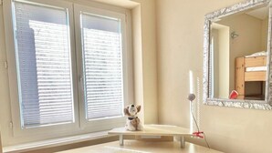 Habitación de esquina con escritorio, espejo y ventana con persianas.