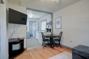 A compact living space with a dining area, kitchenette, and a TV mounted on the wall.